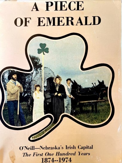 The cover of O’Neill’s centennial town history, published by Holt Co. Historical Society, shows descendants of early settlers raising a shamrock in front of a covered wagon.