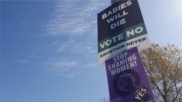 A lightpost with posters attached that are both pro and anti abortion