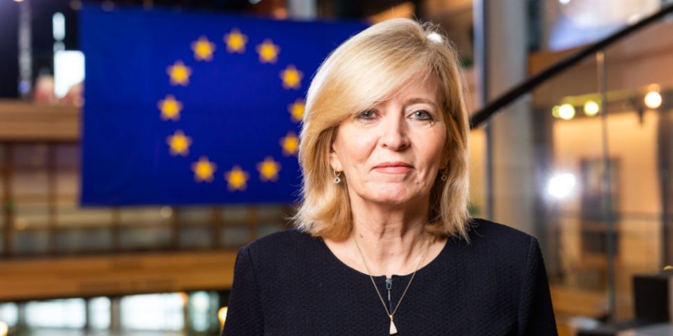 A headshot of Emily O'Reilly standing in front of the flag of the European Union