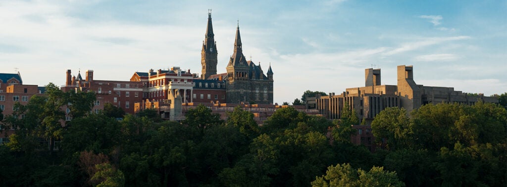 The outline of the georgetown university campus buildings are framed against the blue sky.