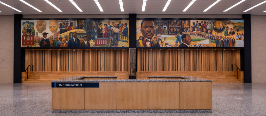 MLK Library front desk, a mural of multiple depictions of MLK in the background done by Don Miller.