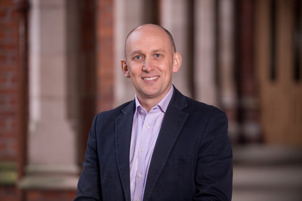 photo of Prof. Muiris MacCarthaigh smiling in front of a blurred background.