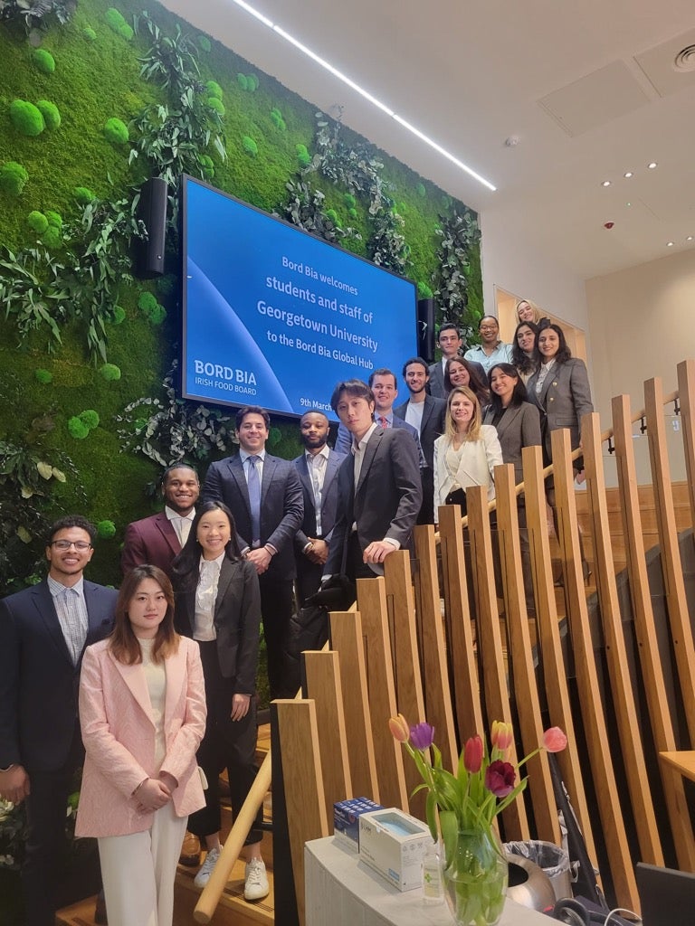 A large group of students stands along a staircase in front of a screen that says "Bord Bia welcomes students and staff of Georgetown University."
