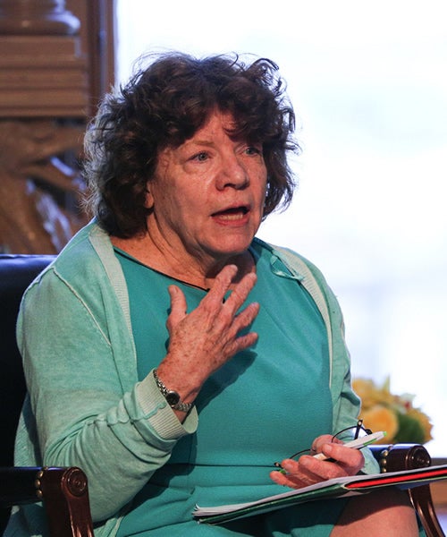 Prof. Jillson at an event in Riggs Library. Wearing a green dress and gesturing with her right hand.